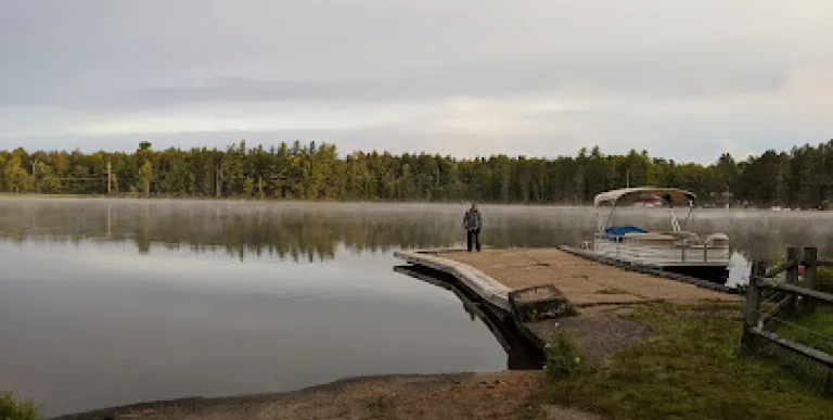 Sturdy boat launch onto a picturesque lake as smooth as glass and ringed with pines