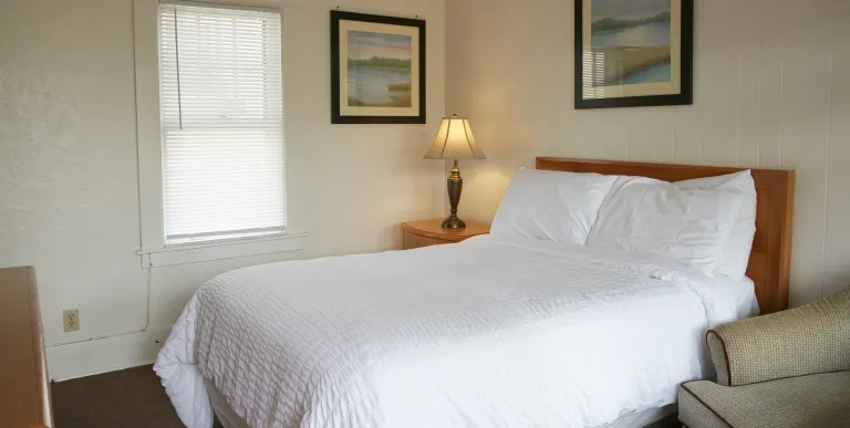 Plush white linens on a king bed in a bright room at The Ashley.