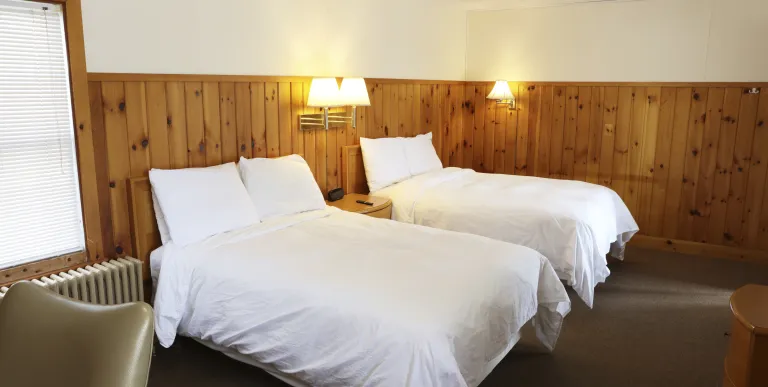 Plush white linens on two queen beds at The Ashley.