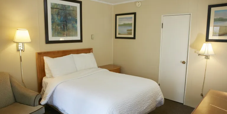 Plush white linens on a queen bed in a yellow walled room at The Ashley.